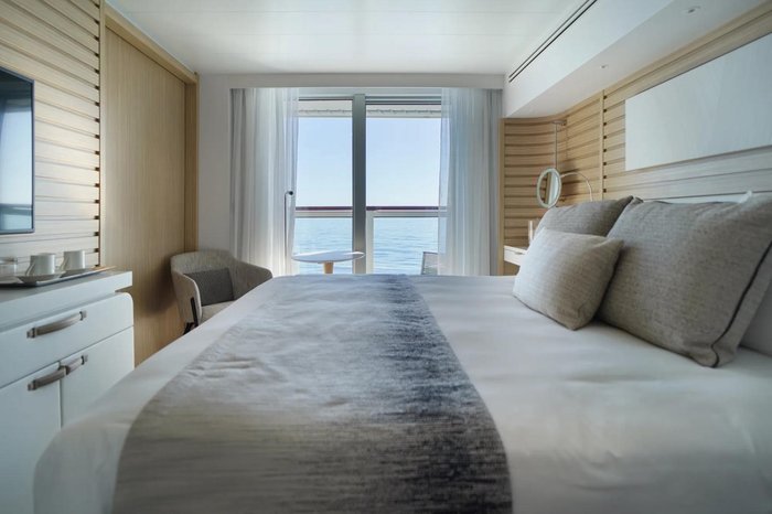 Bright PONANT Explorer-class balcony stateroom with king bed and ocean view