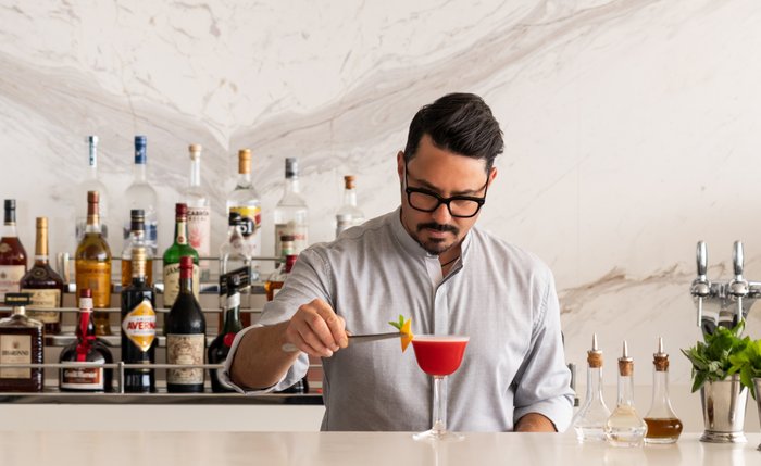 Bartender preparing a cocktail at a marble bar aboard a Ritz-Carlton yacht
